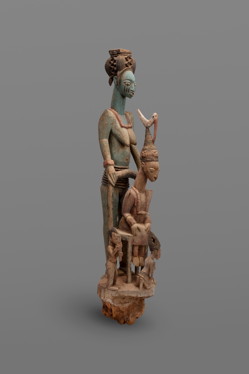 Wooden sculpture of seated king surrounded by family.