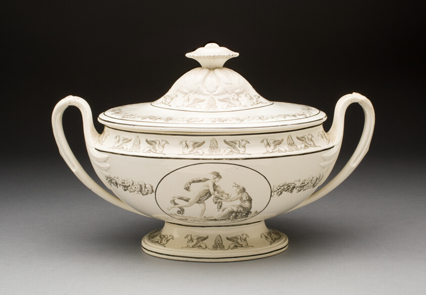 Deep earthenware soup bowl with two swirly designed handles and cover topped with a flower shaped element. The bowl is decorated in black with griffin and palmette pattern on rim and with a scene in an oval depicting a running male figure in a winged helmet handing a baby over to the lady sitting on the ground.