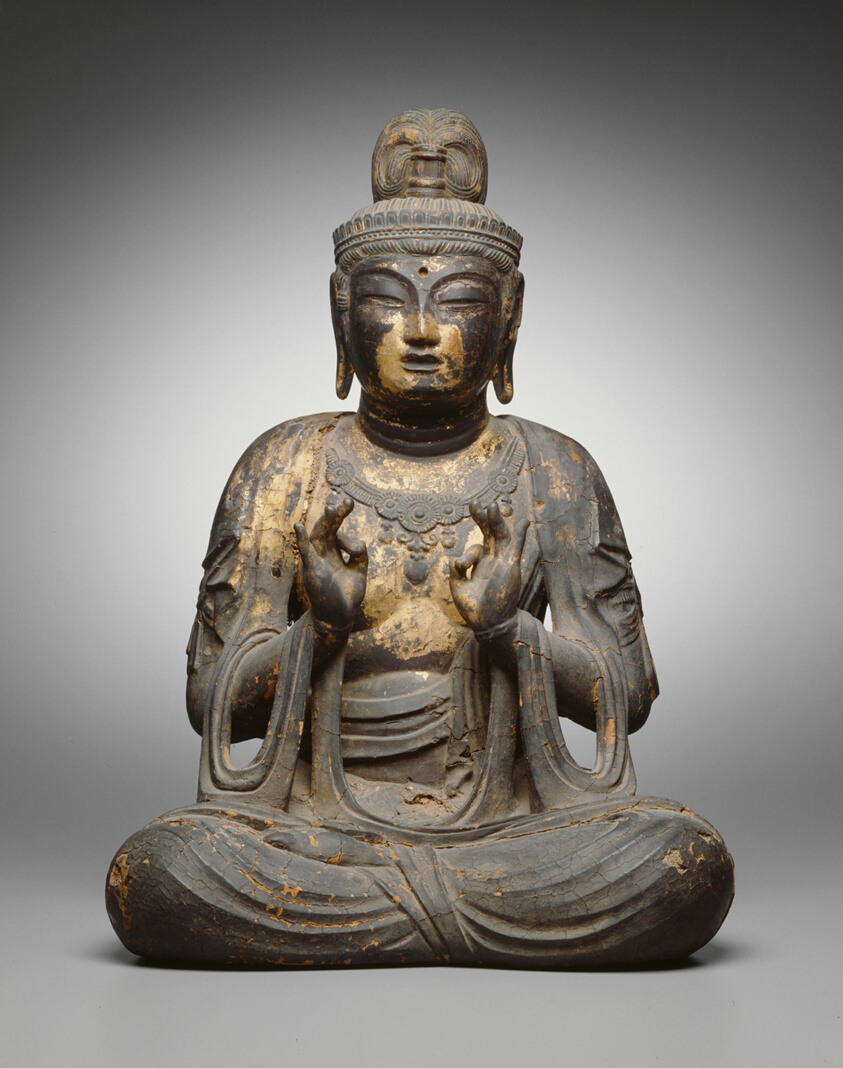 Seated wooden Buddha statue with with forefinger touching thumb.