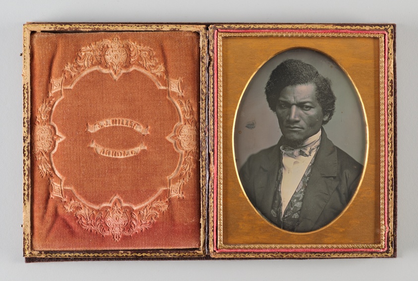 Historical black and white photographical portrait of Black man in a suit, gold frame.