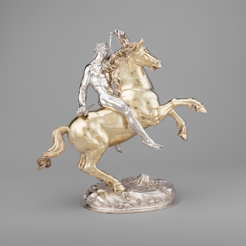Small statue, silver male rider on gold horse on its hind legs.