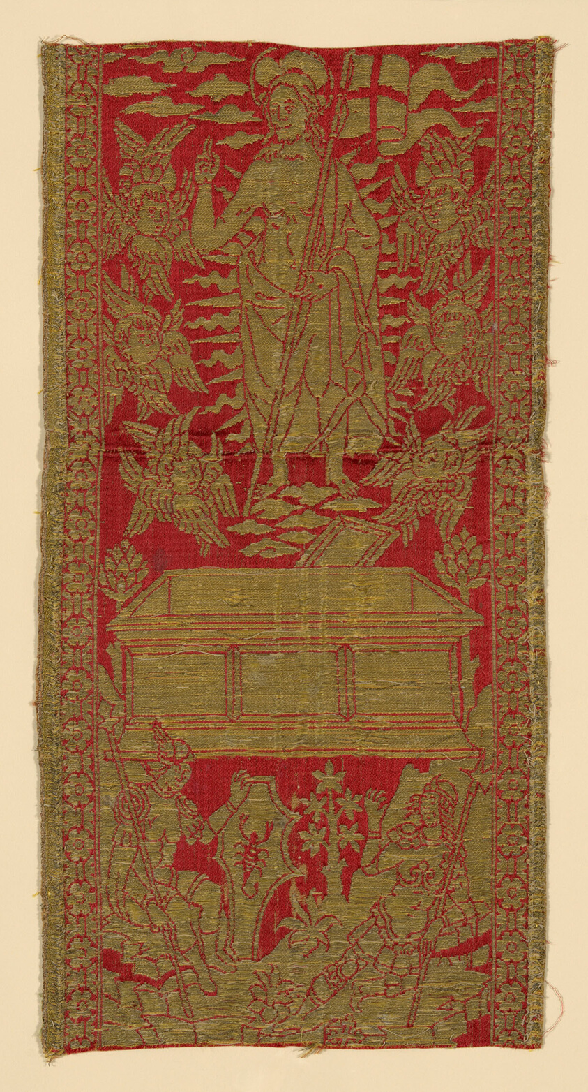 A vertical textile in red and gold depicts a saint holding a flag in the upper center. Two people in armor appear toward the bottom, one holding a shield with a scorpion on it.