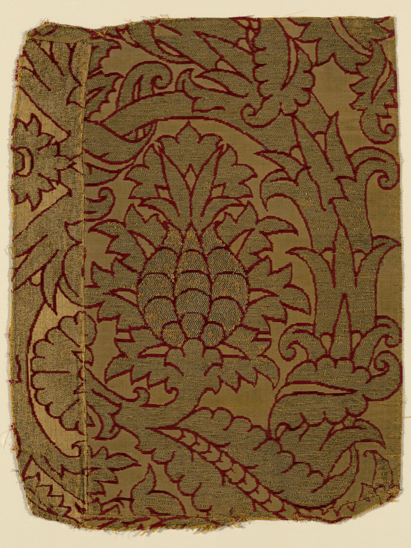 Textile fragment, light brown background with darker patterning of wide vine-line forms with leaves and flourishes, outlined in red thread.