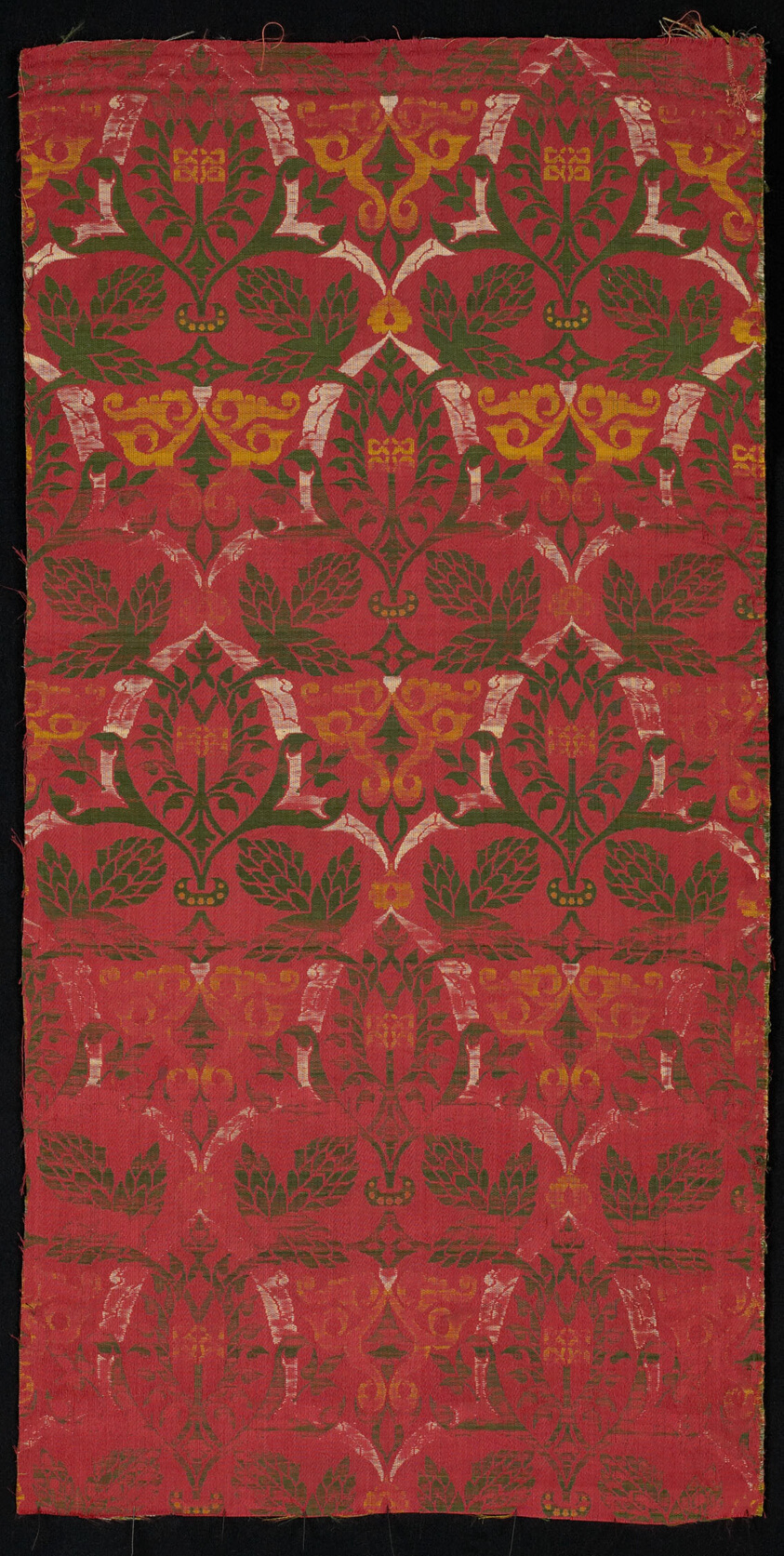 Red silk with plant inspired design in green, white, and yellow.