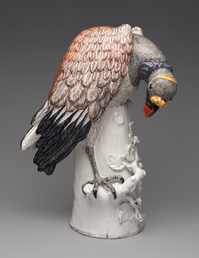 Porcelain vulture with red, black, feathers on white tree stump.