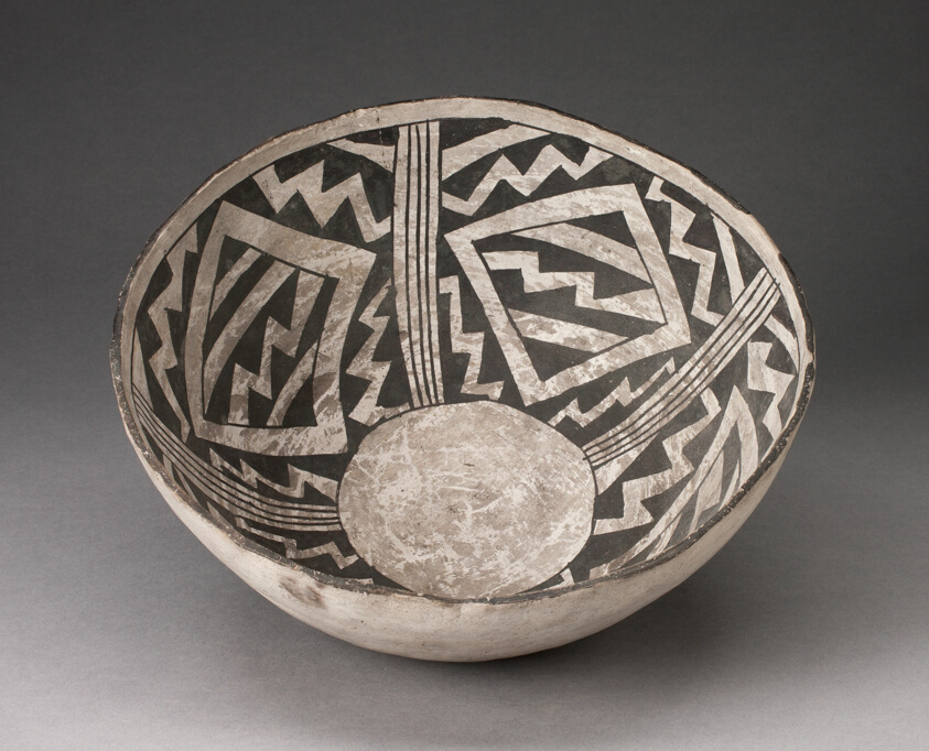 Bone-colored bowl with interior decorations of bone-colored zig-zags, diamonds, and lines on a black background, a circle at the interior base.