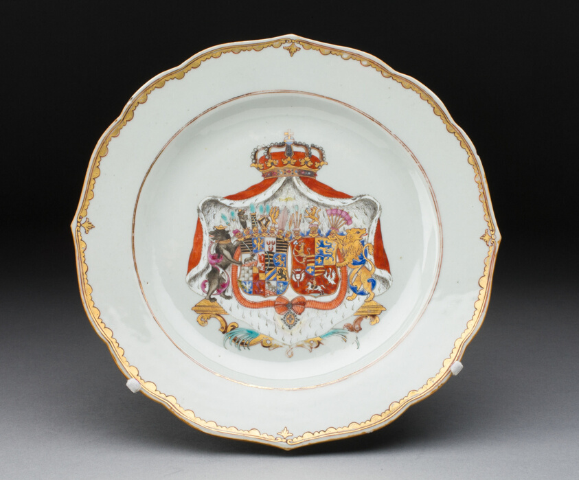 Porcelain plate with enamel depiction of coat of arms and scalloped rim with a gold border.