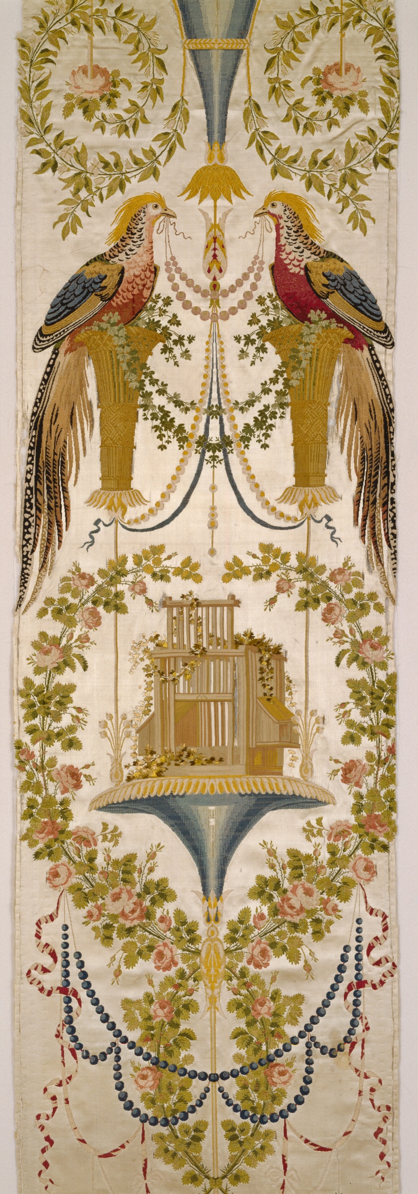 A textile featuring two pheasants in the upper portion facing one another, strands of golden beads held between them in their beaks, symmetrical garlands above and below them, a golden structure near the middle, and curled ribbons embroidered near the bottom.