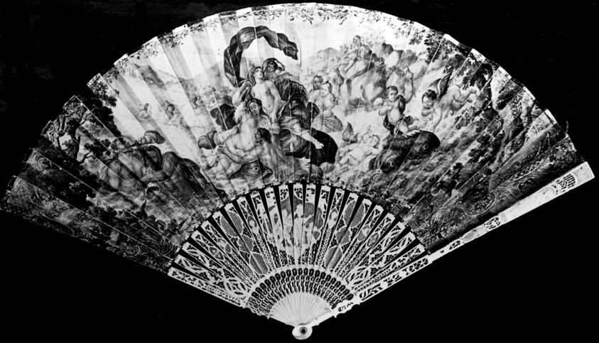 Black-and-white photograph of a fan made of finely carved pieces, featuring nude figures and cherubs among foliage.