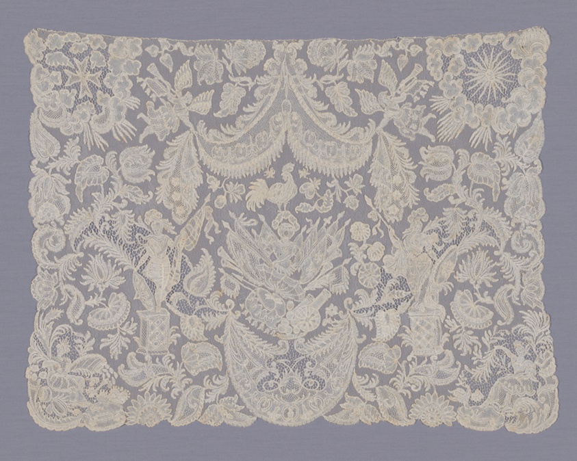A rectangular piece of cream-colored lace fabric boasts a complex design that includes flowers, leaves, roosters, trumpeting angels, armed female warriors, and more.