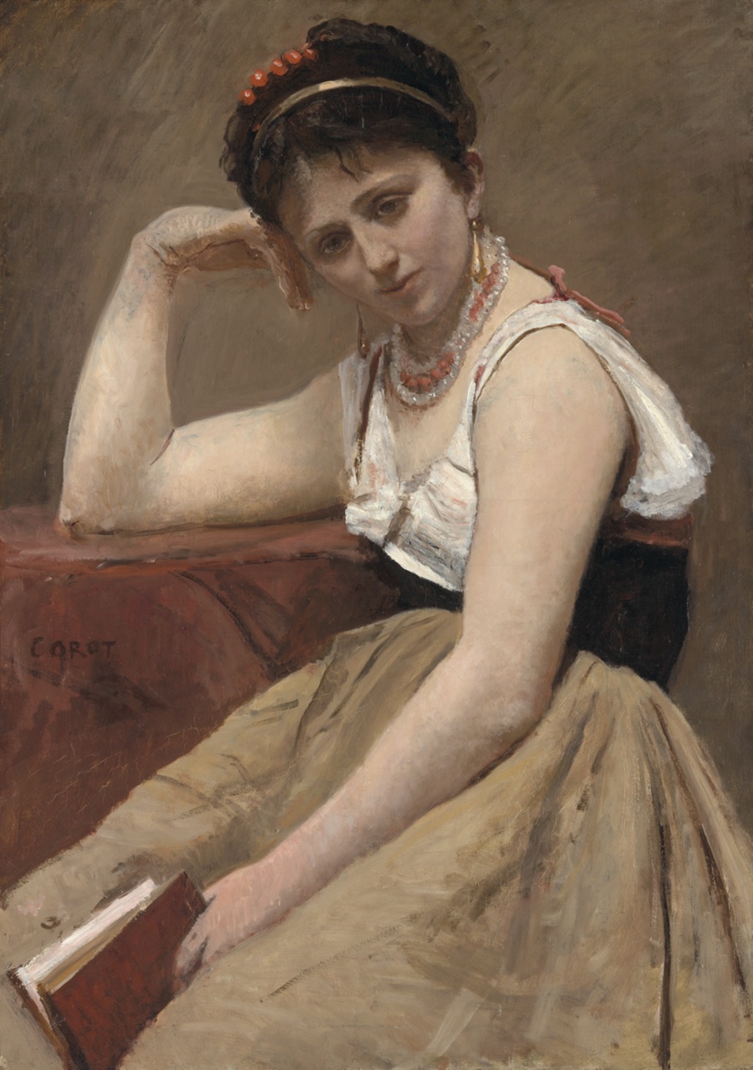 A pensive faced woman sits, slightly hunched, holding a book.