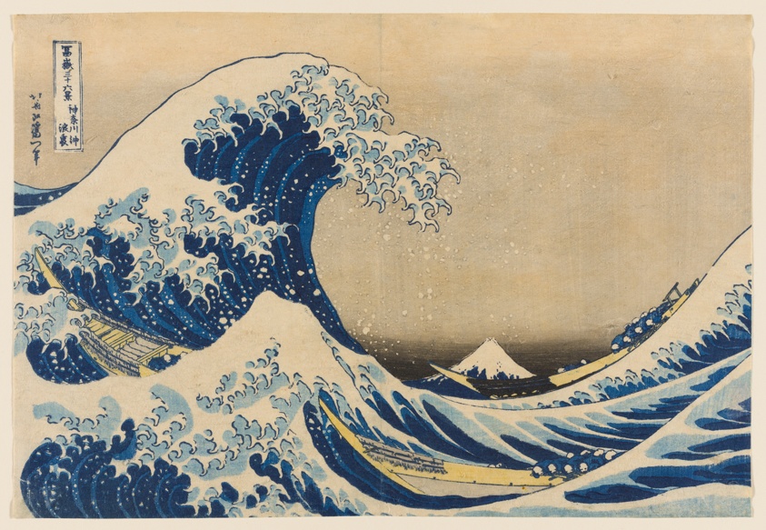 A color woodblock print of a large crashing wave, looms over two narrow boats full of people. Mt Fuji in the background. There is a faint peach colored sky.