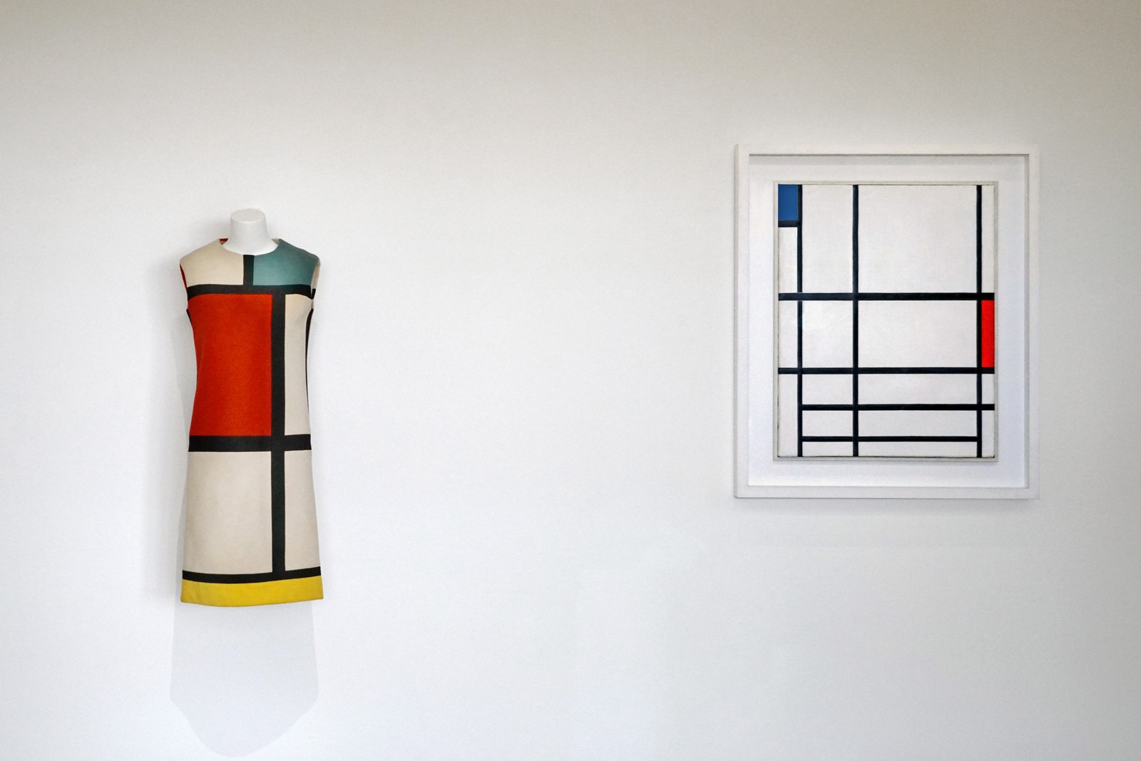 A Saint Laurent dress with black dividing bands and red, blue-green and yellow panels displayed beside a Mondrian painting at the Centre Pompidou.